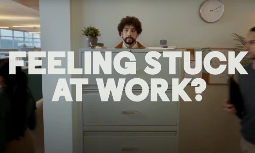 A man is stuck in a filing cabinet with the words, 'Feeling stuck at work?'