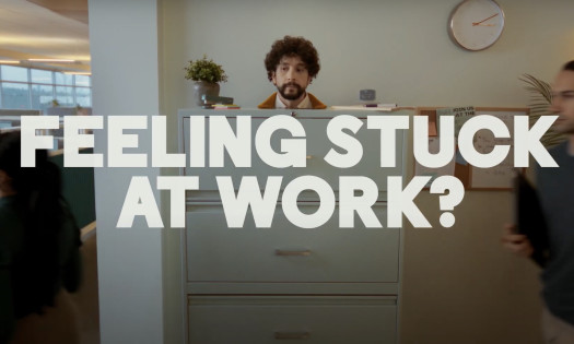 A man is stuck in a filing cabinet with the words, 'Feeling stuck at work?'