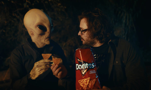 Alien and the spot's main character enjoying a bag of Doritos