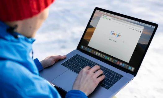 A man searching on Google using his laptop with a snowy background
