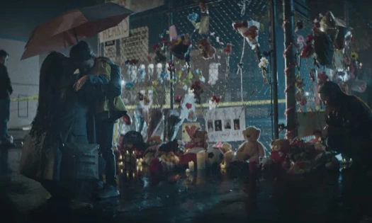 Little girl hugging her mom after offering a teddy bear at a school shooting memorial
