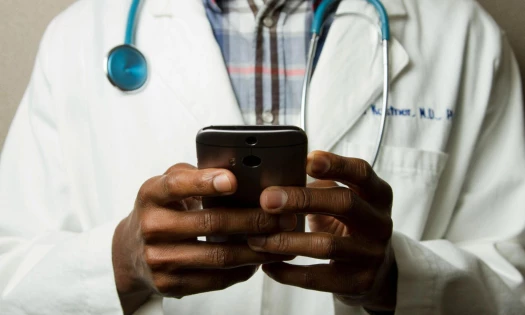 Faceless doctor holding a phone.