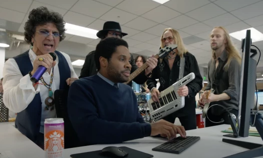 A rock band playing as a man works in the office