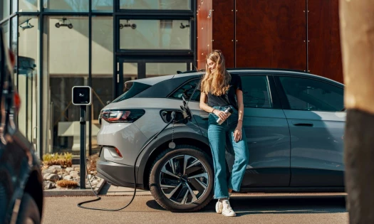 A woman standing next to her electric car while it charges
