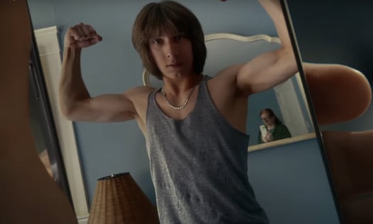 A teen showing off his muscles with the mirror showing his mom taking the photo
