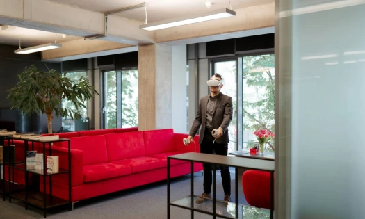A photo of a person playing a virtual reality game in a modern open-space office.