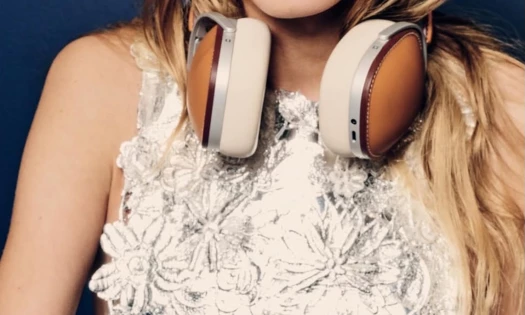 A girl in a white dress with the new Hermes headphones on her neck