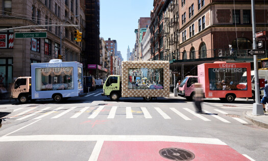 Three trucks featuring transparent glass displays cruise through the streets of Manhattan, showcasing Urban Outfitters' back-to-school campaign.