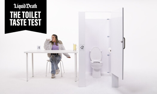 A woman sipping on a mug, as she sits next to a cubicle