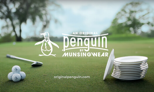 The text "An Original Penguin by MunsingWear" with the penguin logo, golf balls, and a stack of plates on the golf course