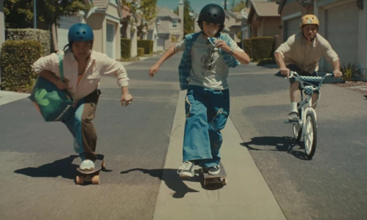A mom with an Instacart bag and her two sons skateboard and bike in the neighborhood
