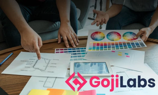 Two people discusses color schemes and mobile app features, with Goji Labs' logo in the corner.