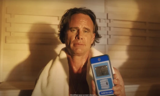 Walton Goggins in a sauna holding up his cellphone with Walmart's app opened