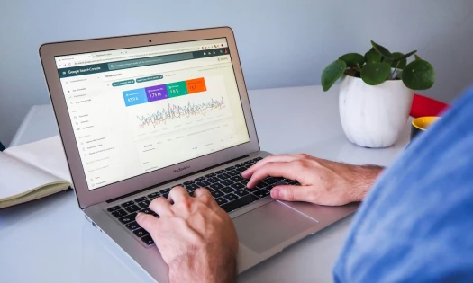 Person using macbook air on white table, viewing Google Search console data
