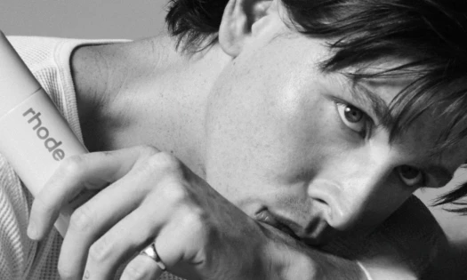 A black-and-white closeup shot of Harris Dickinson holding rhode's Glazing Mist