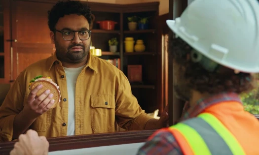 A man holding a sandwich while talking to another man
