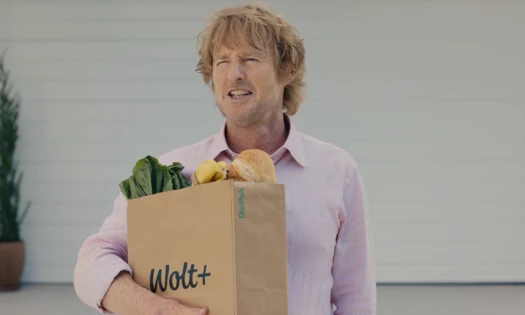 Owen Wilson carrying a Wolt paper bag