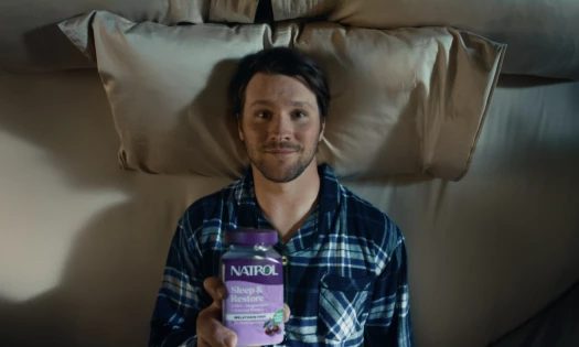 Josh Allen in bed holding up a bottle of Natrol
