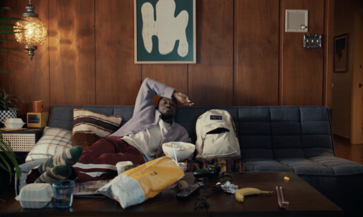 A man and his singing Jansport bag sitting on a couch