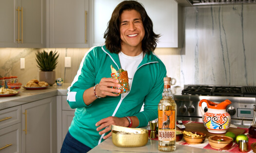 Cristo Fernández holding up his signature cocktail made with Tequila CAZADORES