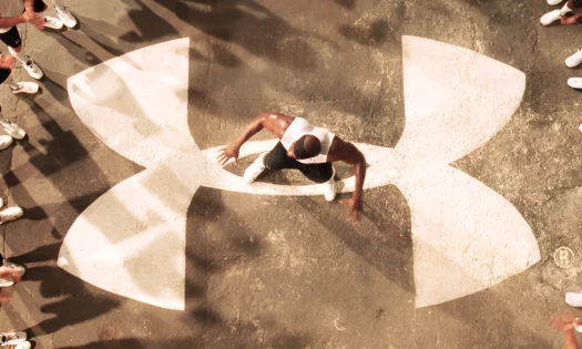 Eric "Big E" Ogbogu standing at the center of a big Under Armour logo with athletes clapping surrounding him from the brand's first national TV ad, "Protect this House"