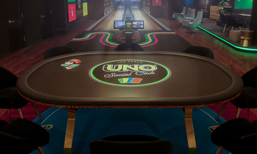 What looks to be a gambling table at the casino floor with the logo of UNO Social Club in the middle