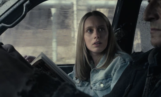 A woman looks at the driver while reading her book
