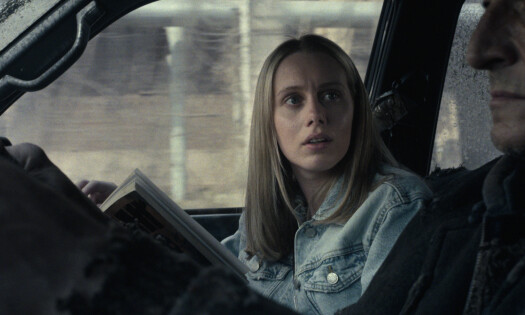 A woman looks at the driver while reading her book