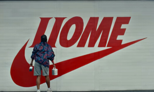 A person looks at a Nike logo that writes "HOME"