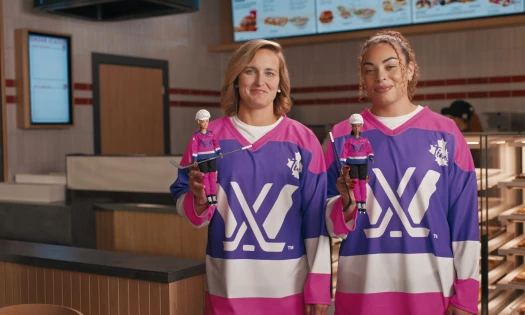 Two athletes pose in their Barbie x Tim Hortons branded jersey and dolls
