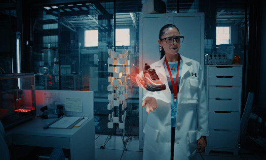 A woman in the lab holding up a levitating Under Armour HALO Sneaker