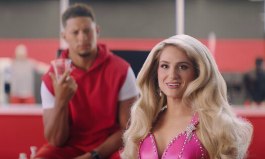 Meghan Trainor looking at the camera with Patrick Mahomes in the background
