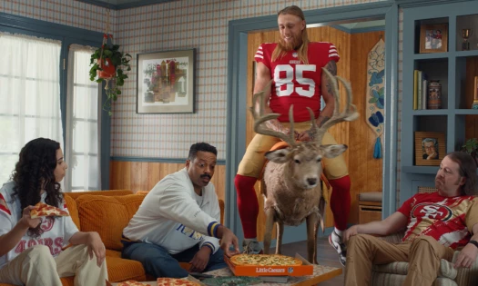 George Kittle riding a deer while other people eat Little Caesars