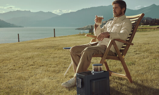 Brad Pitt sitting outside with a glass of espresso with the De’Longhi coffee machine beside him