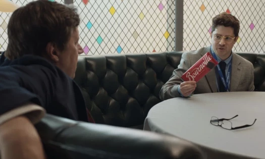 Two men talk while one of them holds up a Bournville chocolate bar