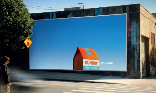 A woman looks at a Dunkin' At Home billboard in Bushwick