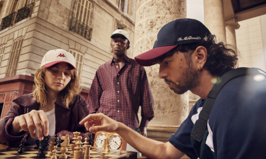 Two people playing chess as they sport the new McDonald's x Kappa collection