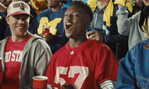 Sports fans cheering on with a cup of Coca-Cola in hand