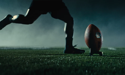A football player about to kick an NFL-branded football