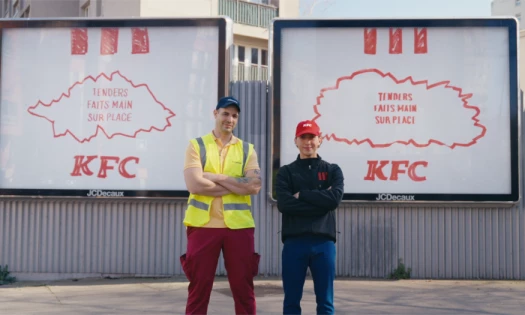 Two man stand in front of two hand-drawn OOH ads by KFC