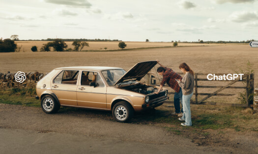 Two people check the front of their car while on a roadtrip