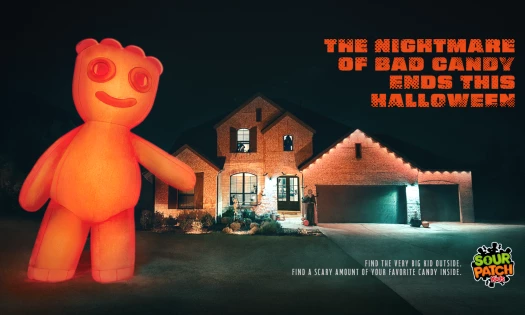 A giant inflatable Sour Patch Kid towers over a house