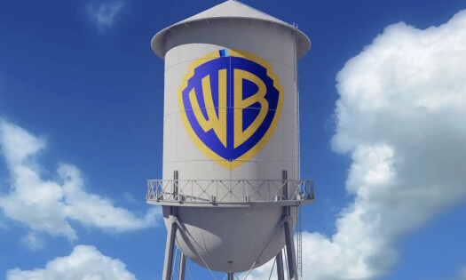 A white water tower with the Warner Bros. logo against a cloud background