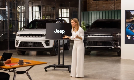 Iliza Shlesinger speaking to a panel with a black and white 2026 Jeep Grand Wagoneer behind her