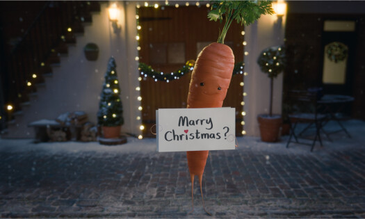 Kevin the Carrot holding up a sign that says 'Marry Christmas?'