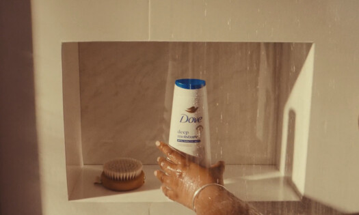 A person grabbing a Dove shower cream in the shower