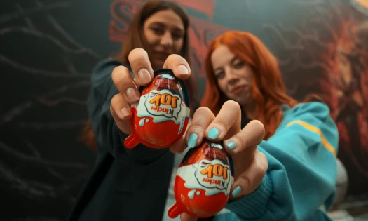 Two girls hold up the Kinder Joy x Stranger Things chocolate