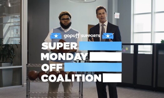 Druski and Tom Brady standing inside a typical office, in front of a Gopuff delivery bag