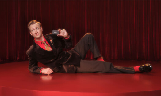 A man holding up a Red Lobster card while sitting on the floor