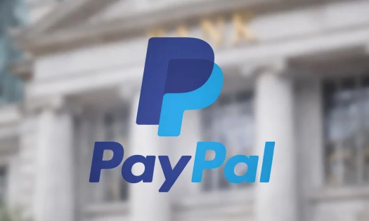 The PayPal logo shown in front of a blurred background showing a banking institution